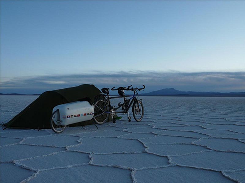 Tente, vélo et remorque au crépuscule dans un vaste paysage